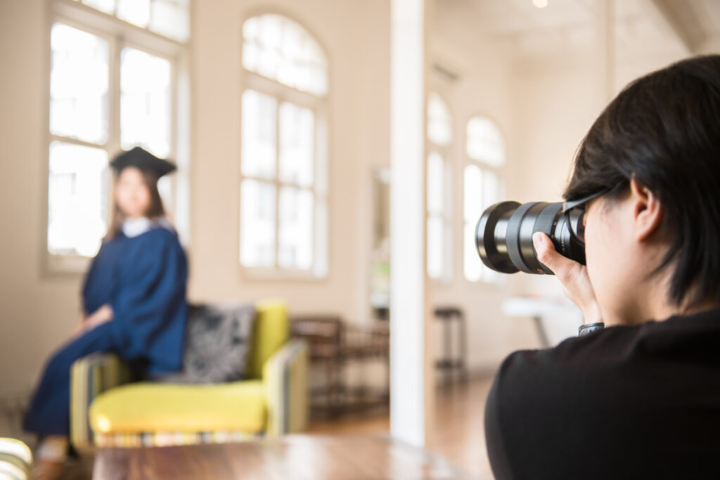 Behind the Scenes of a Photography Shoot Behind the scenes photo of a photographer taking portraits of a graduate in graduation gown and hat