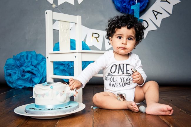 Baby Cake Smash Photography Singapore one year old birthday boy with cake and blue party decorations