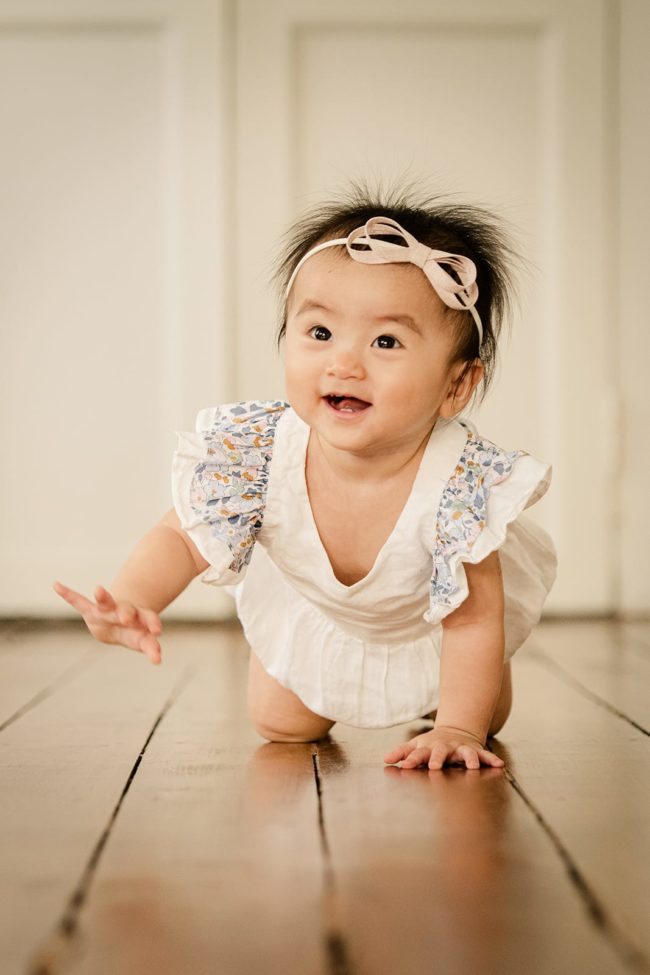 Baby First Year Photography Singapore smiling toddler crawling with pink bow and white dress