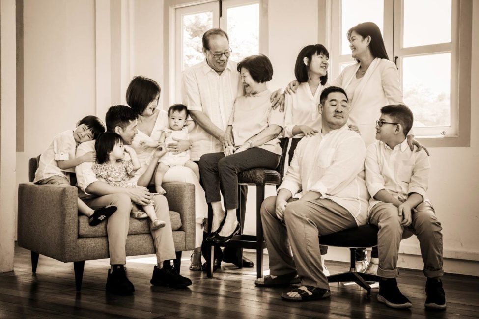 Generation photoshoot of large family of grandparents, parents, children and grandchildren sepia tone indoor portrait photography