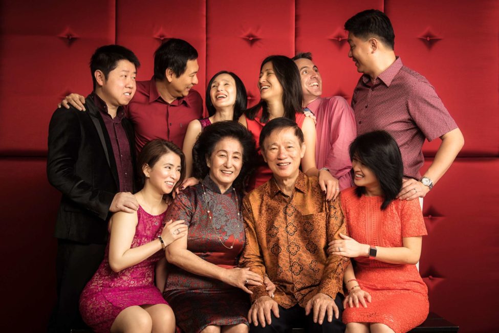 Multi generation photoshoot session with whole family dressed in red clothing and warm colours
