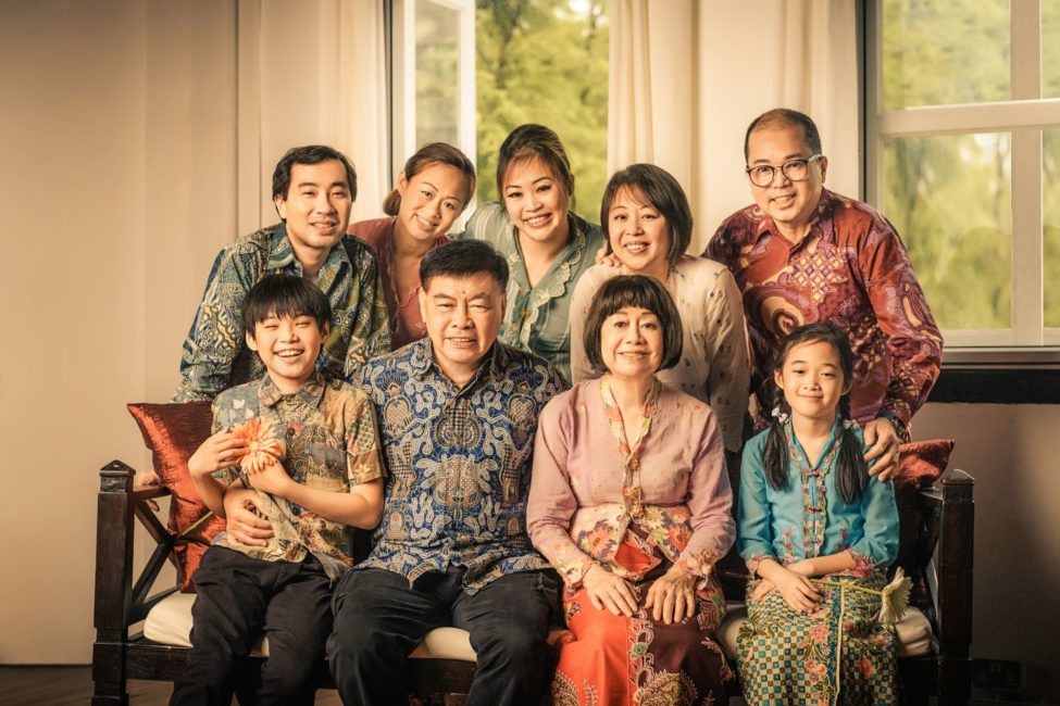 Generation photoshoot package Singapore of a Peranakan family in traditional cultural clothing sitting and posing around wooden sofa