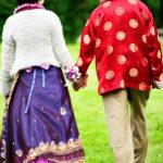Bridal Photography Singapore bride and groom in traditional indian clothing holding hands and walking in grassy field outdoor photoshoot