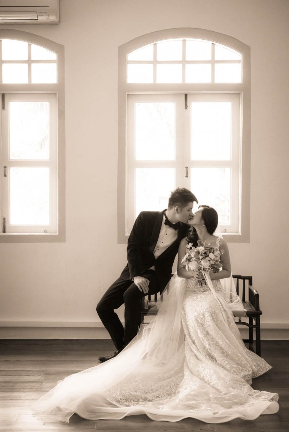 Bridal Photography Singapore bride and groom sitting down and kissing indoor black and white portrait photography