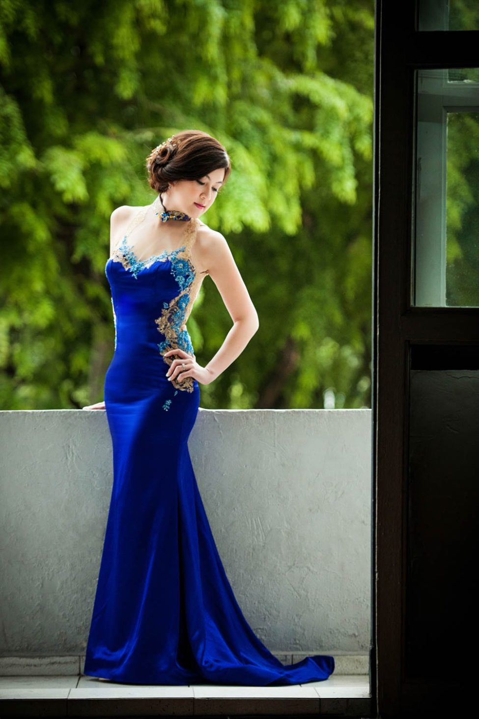 Bridal Photography Singapore bride in blue ballgown posing hand on hip natural light photoshoot with nature landscape background