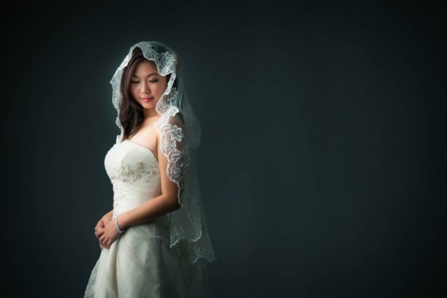 Bridal Photography Singapore bride in wedding dress and veil side profile portrait with black background