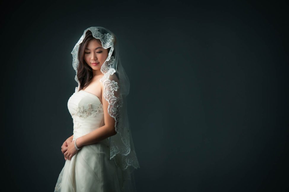 Bridal Photography Singapore bride in wedding dress and veil side profile portrait with black background