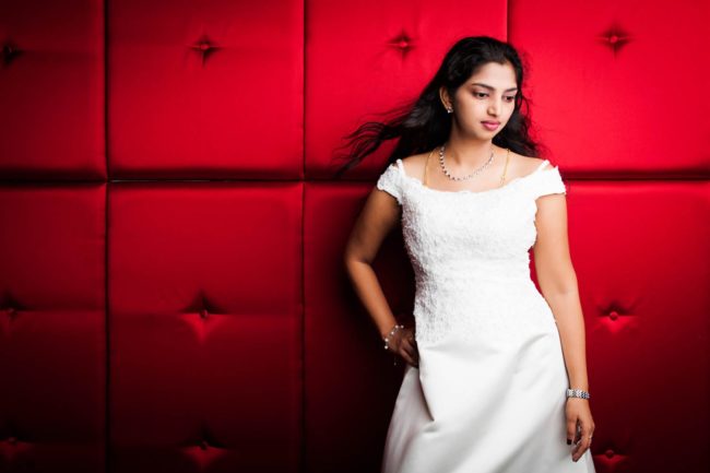 Bridal Photography Singapore bride in white wedding dress posing at red cushioned wall portrait photography