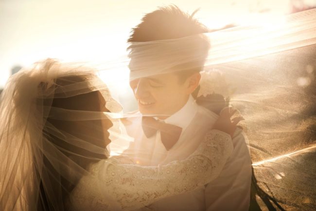 Bridal Photoshoot Singapore bride and groom under wedding veil with natural lighting sepia tone portrait