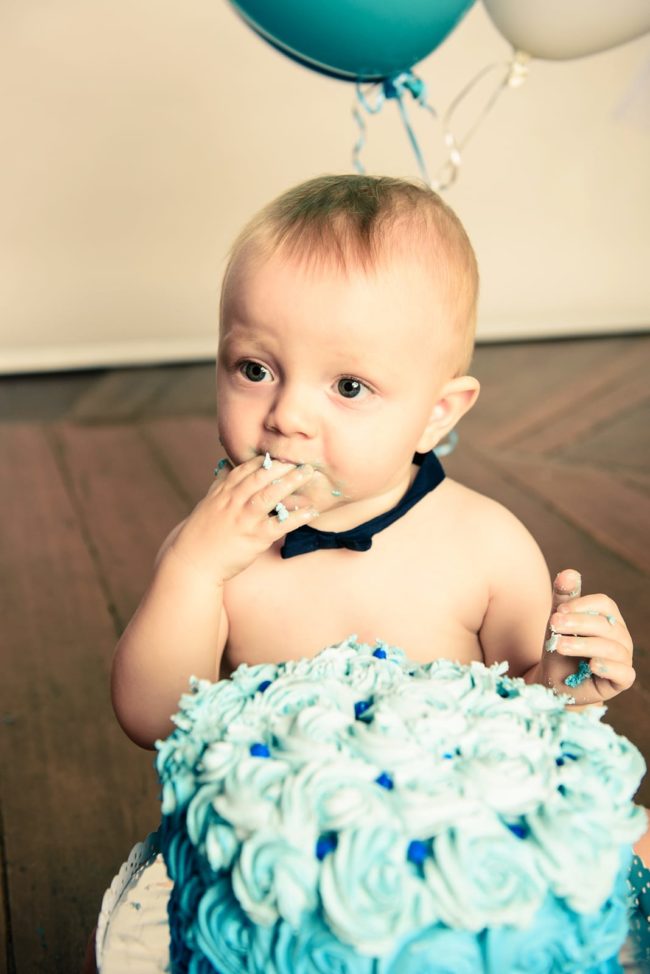 Cake Smash Photography Singapore baby boy wearing black bow tie and eating blue cream cake