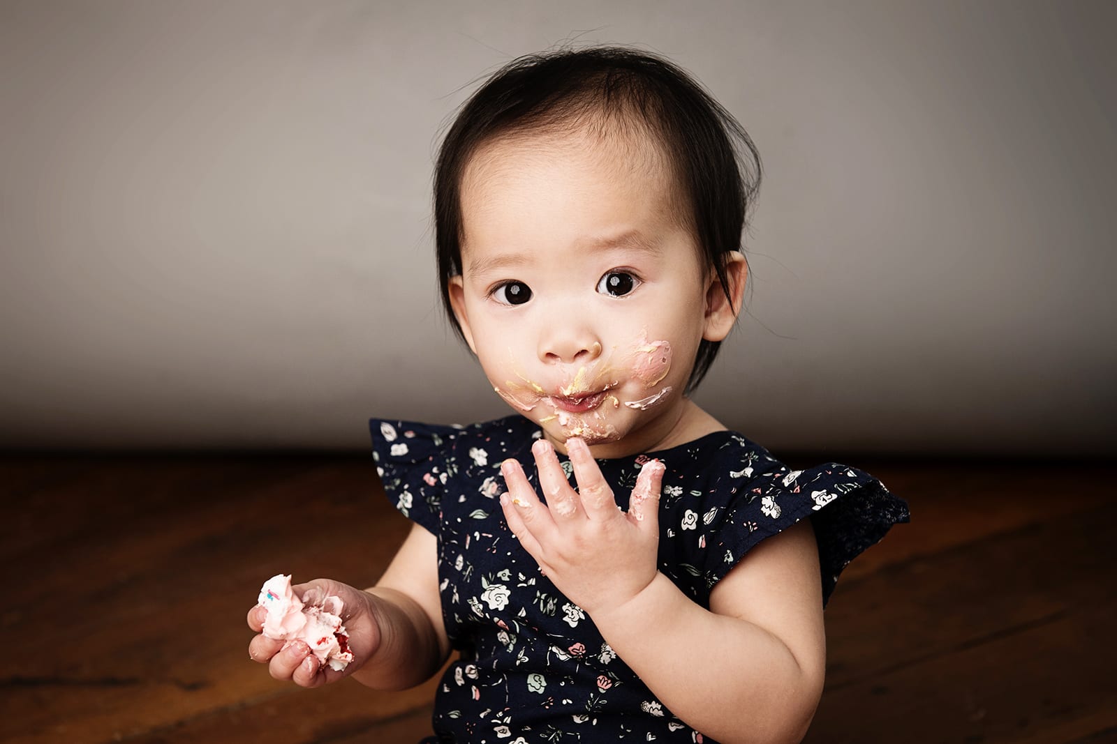Cake Smash Photography Singapore baby toddler young girl in floral dress eating cake and cream with hands