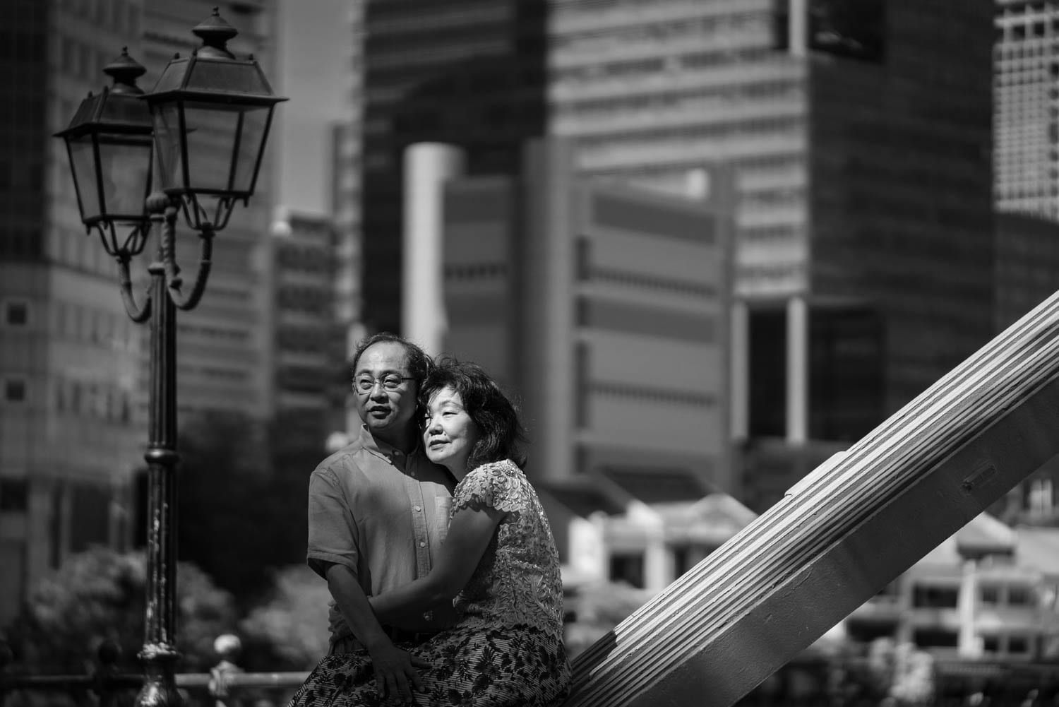 Couple Photography Singapore elderly couple hugging looking at scenery outdoor photoshoot black and white portrait at Singapore River