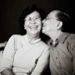 Couple Photography Singapore elderly couple sitting down man kissing smiling woman's cheek black and white portrait photography