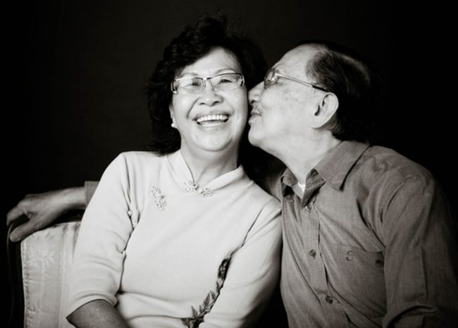 Couple Photography Singapore elderly couple sitting down man kissing smiling woman's cheek black and white portrait photography