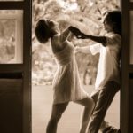 Couple Photography Singapore man and woman dance posing at door frame indoor photoshoot sepia tone portrait