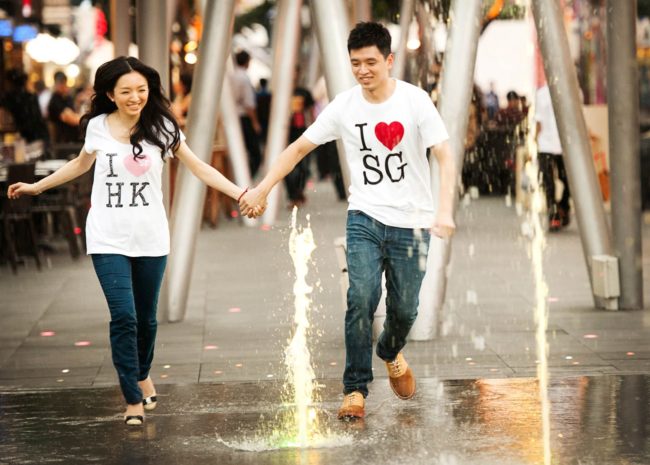 Couple Photography Singapore man and woman holding hands playing in water fountain outdoor photoshoot at Clarke Quay