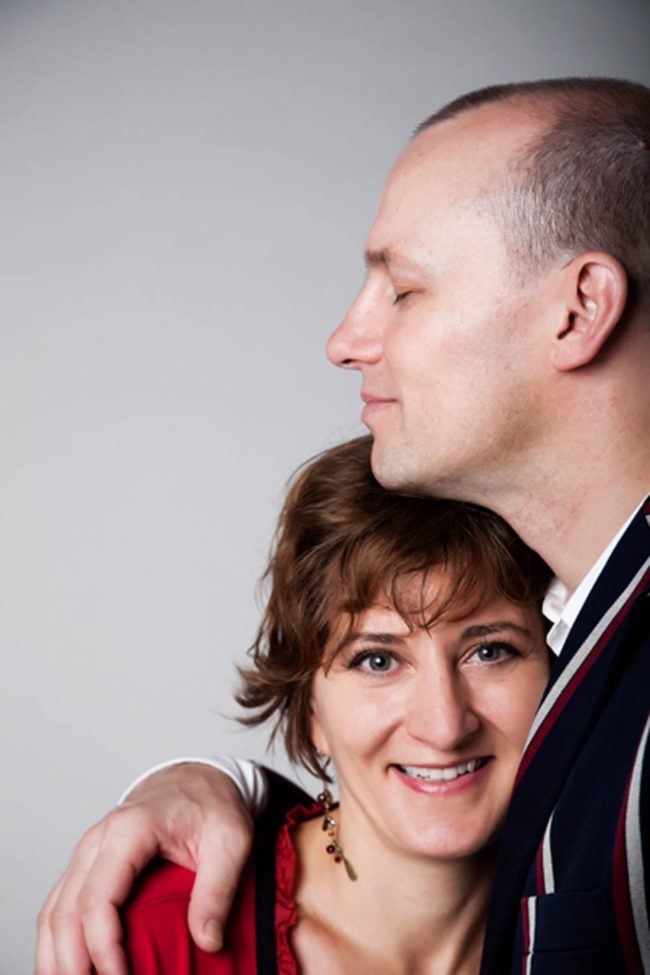 Couple Photography Singapore smiling woman in red blouse and earrings head leaning on man's chest