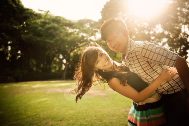 Couple Photoshoot Singapore man holding woman by the waist both smiling natural light outdoor photography