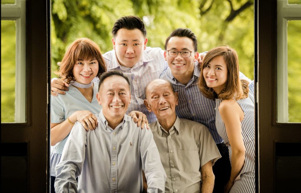 Family generation photoshoot with grandfather, parents and grandchildren smiling with nature landscape background