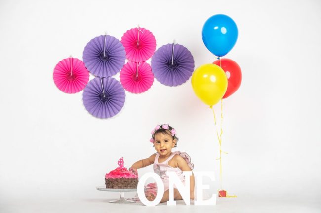 First Year Cake Smash Photography Singapore baby young girl with colourful decorations and pink cake
