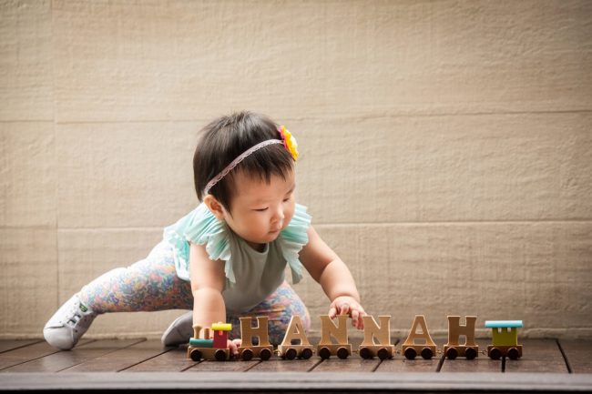 First Year Photography Singapore toddler young girl baby with flower headband playing with name wooden blocks train toy
