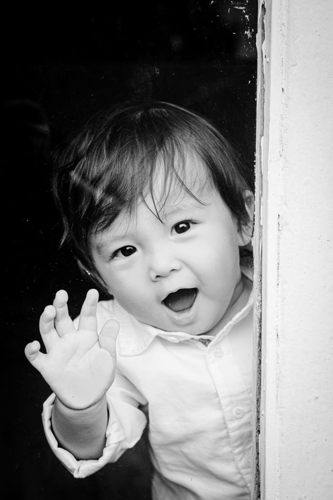 First Year Photography Singapore toddler boy in dress shirt smiling and waving black and white portrait photography