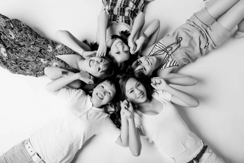 Glamour Photography Singapore 5 smiling friends photoshoot lying on the floor and holding hands black and white portrait photography