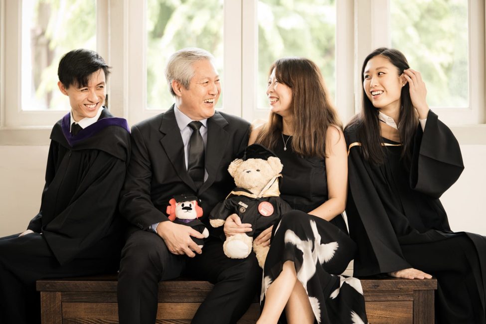 Graduation Photoshoot Singapore smiling family candid portrait with parents holding lion and teddy bear graduate soft toys