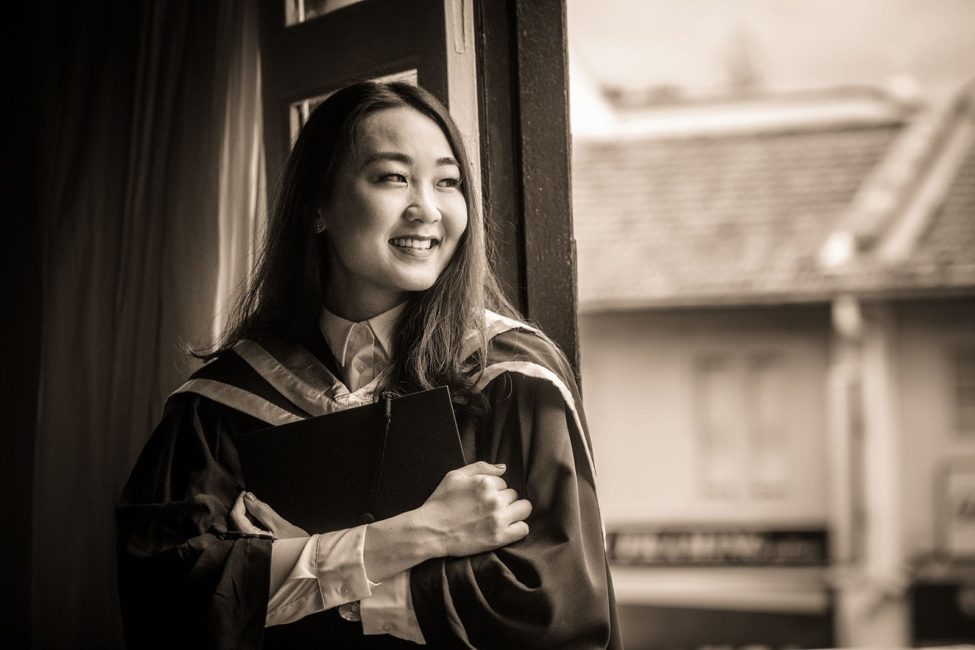 Graduation Photoshoot Singapore female graduate smiling and holding mortar board portrait black and white