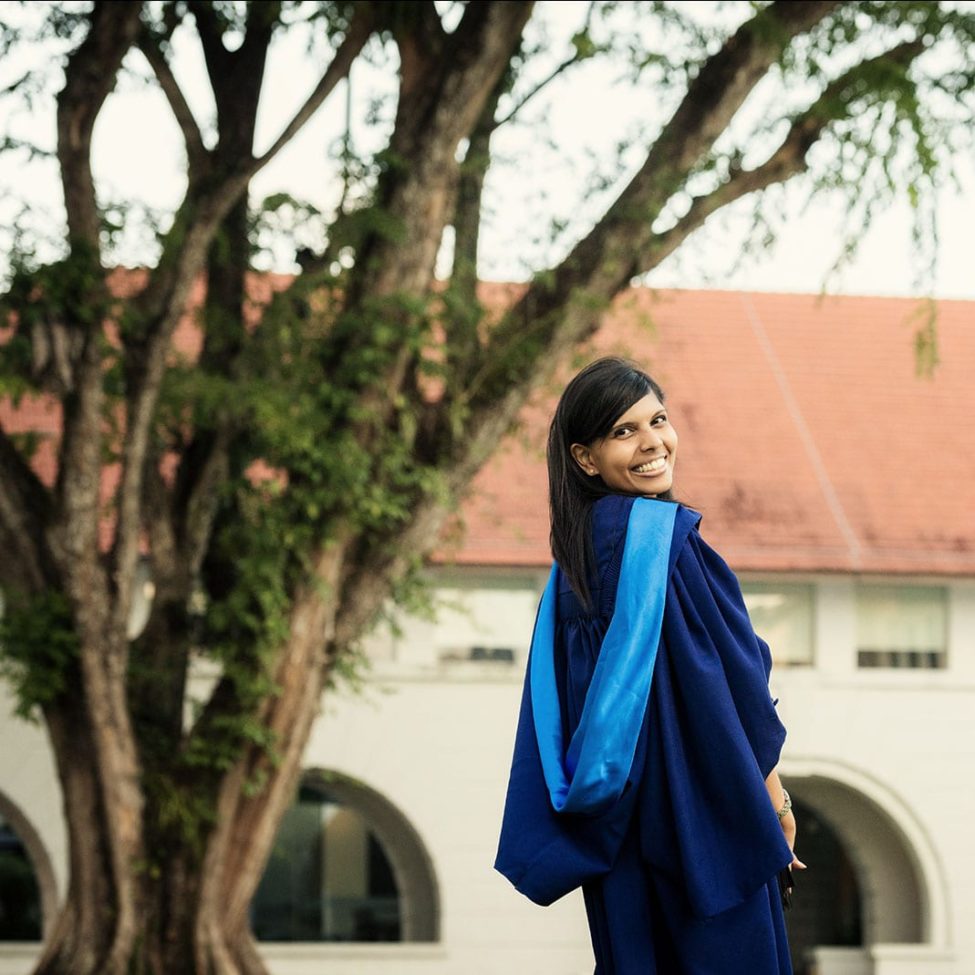 Graduation Portraits Singapore female graduate smiling back view outdoor photoshoot with tree and old buildings