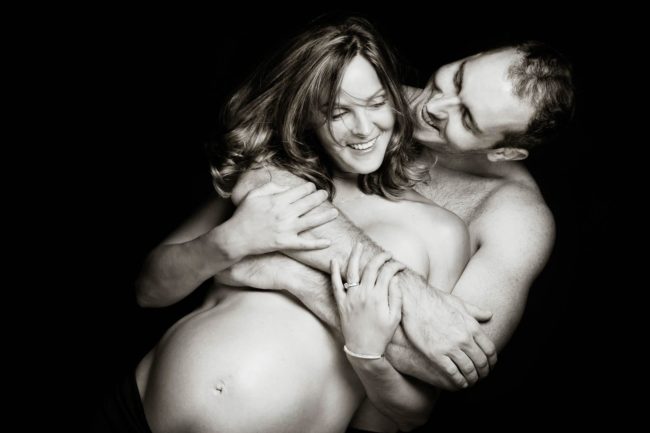 Maternity Photoshoot Singapore husband hugging semi-nude pregnant wife both smiling black and white portrait photography
