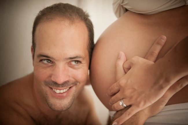 Maternity Photoshoot Singapore smiling husband listening for baby at pregnant wife's belly and holding hands