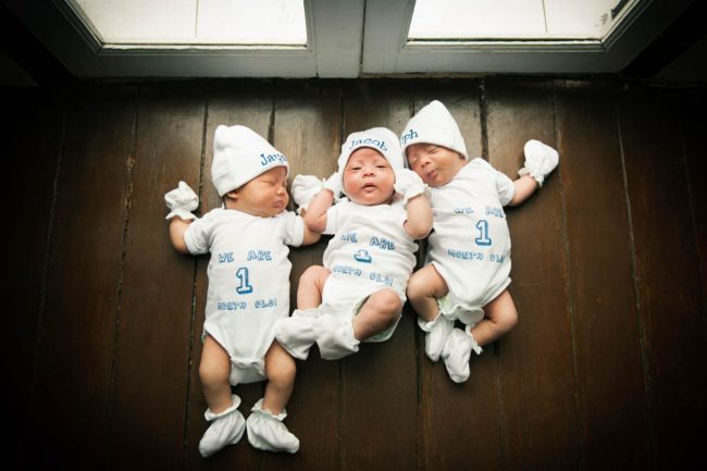 Newborn Photography Singapore 3 baby triplets lying together on wooden floor for photos to commemorate first month milestone
