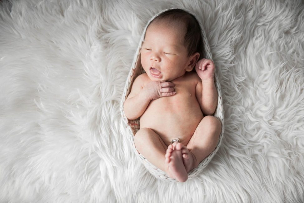 Newborn Photography Singapore baby mouth open and curled up sleeping on white fur rug