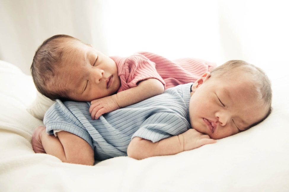 Newborn Photography Singapore boy and girl twins sleeping on each other's backs over white soft pillow