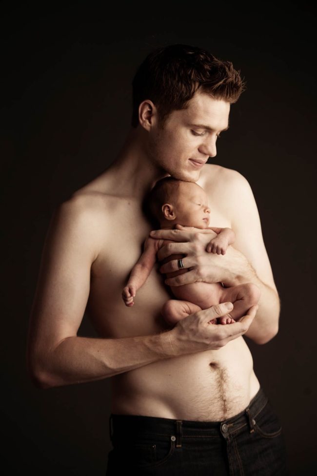 Newborn Photography Singapore father holding and posing with baby with black backdrop