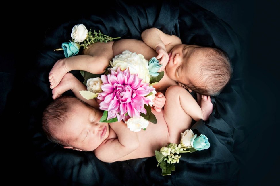 Newborn Photoshoot Singapore 2 babies twins curled up with flowers on black cloth