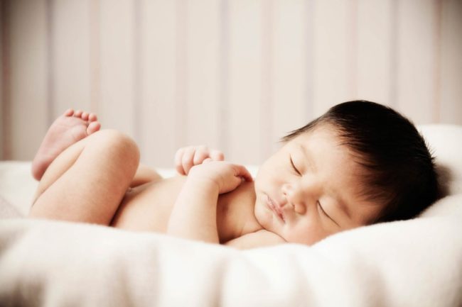 Newborn Photoshoot Singapore baby curled up sleeping on white cushion
