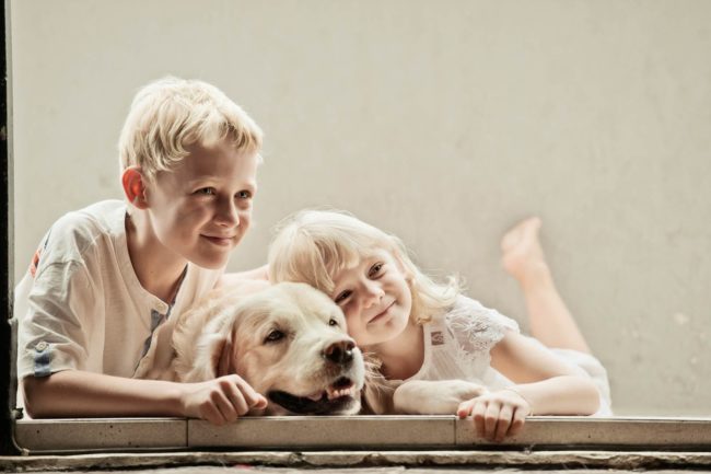Pet Photography Singapore 2 young children smiling and leaning on white dog natural light photography