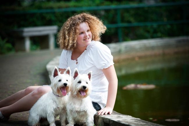 Pet Photography Singapore young blonde girl smiling with 2 white dogs outdoor photography