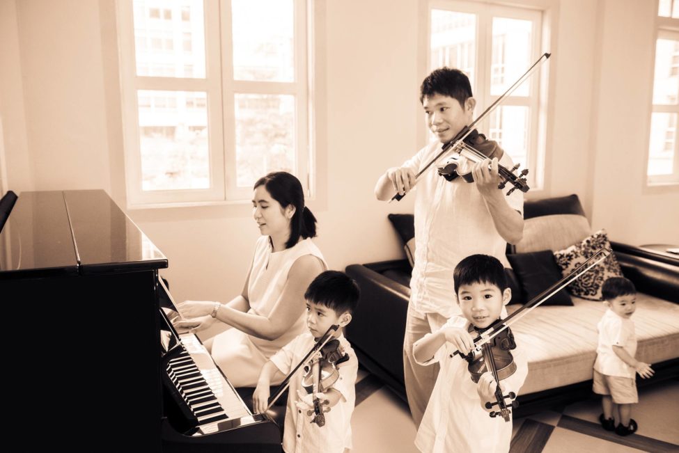 Family photoshoot package singapore of musically inclined family with parents and three young boys playing piano and violins