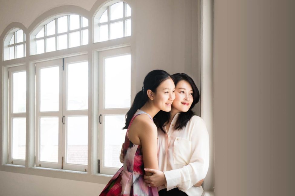 Professional family photoshoot of mother and daughter hugging in natural light photo studio