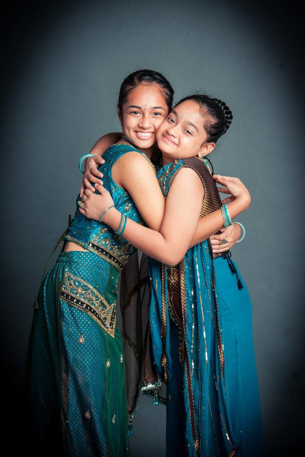 Family kids photography two girl children dressed in cultural Indian dressing blue saris hugging and smiling