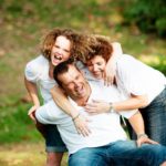 Family kids photography outdoors nature session of candid mother and child hugging father sitting on tree trunk