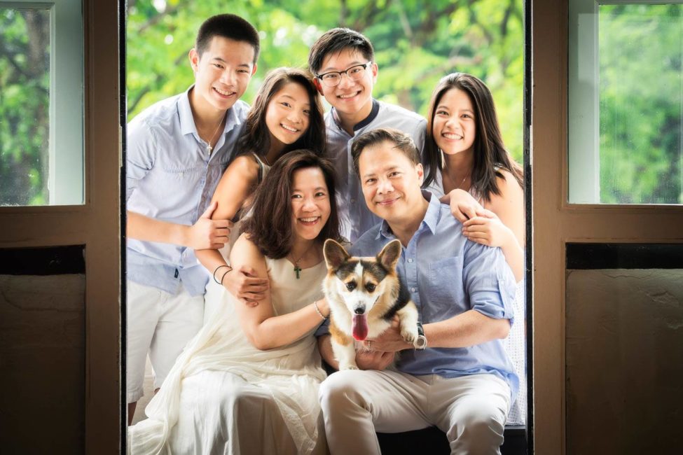 Family photoshoot studio photography of family of six huddled together with pet dog corgi