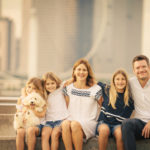 Outdoor family kids photography session of a smiling Caucasian family with 3 children and a pet dog with the Singapore Flyer in the background