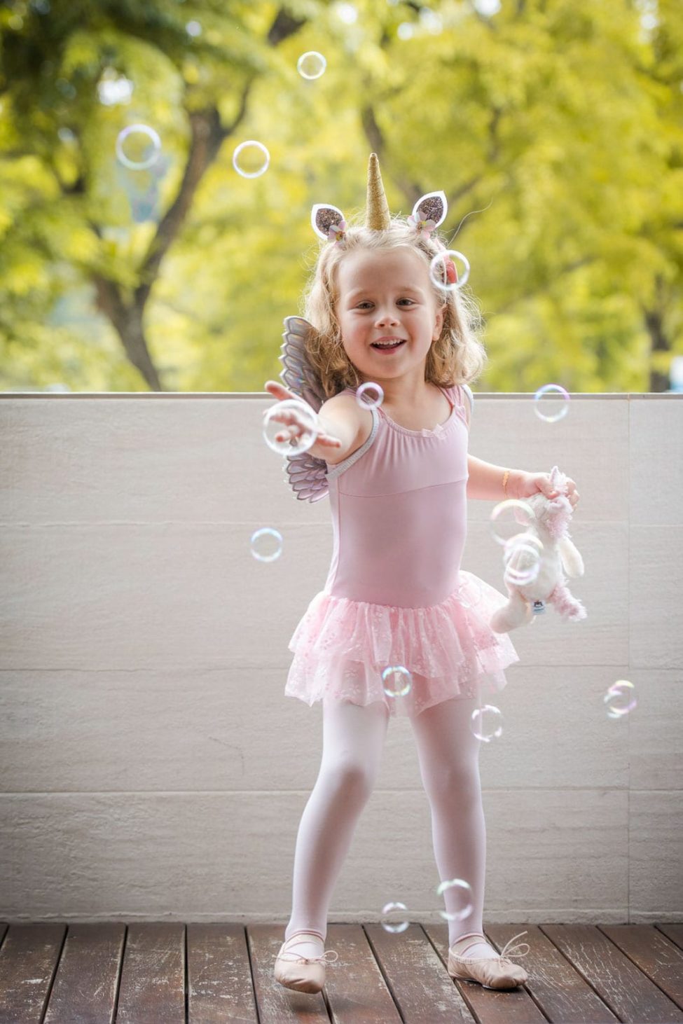 Children Singapore Photoshoot Natural young girl happily playing with bubbles in unicorn ballerina costume