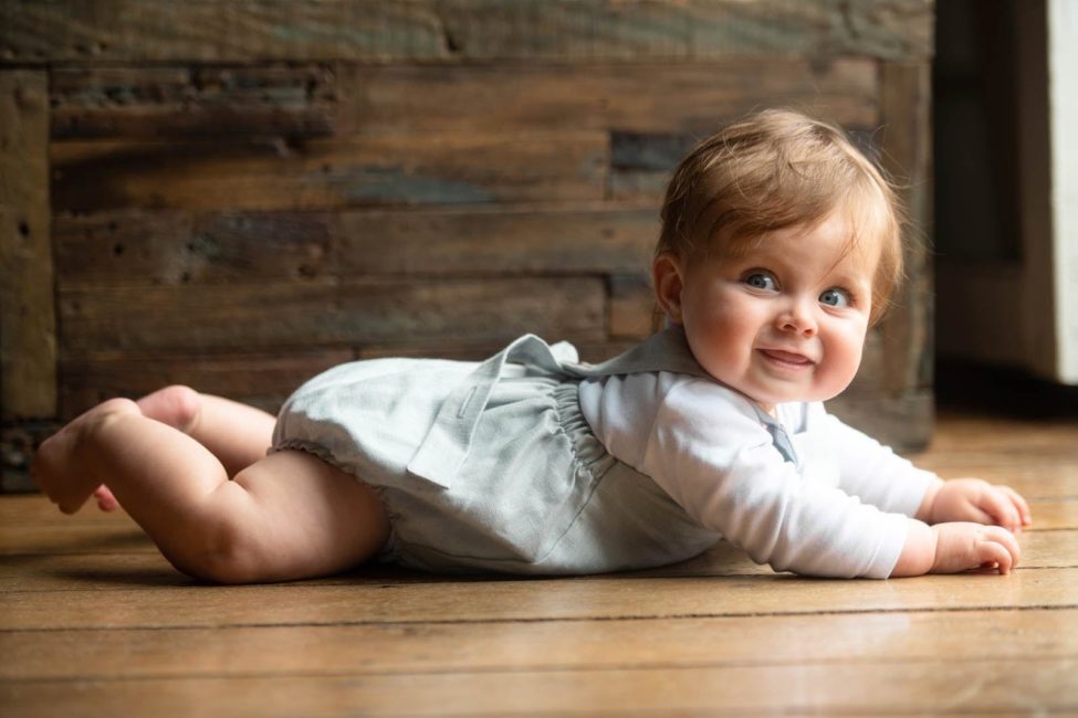 Kids Indoor Photoshoot Singapore smiling toddler lying on belly wearing overalls