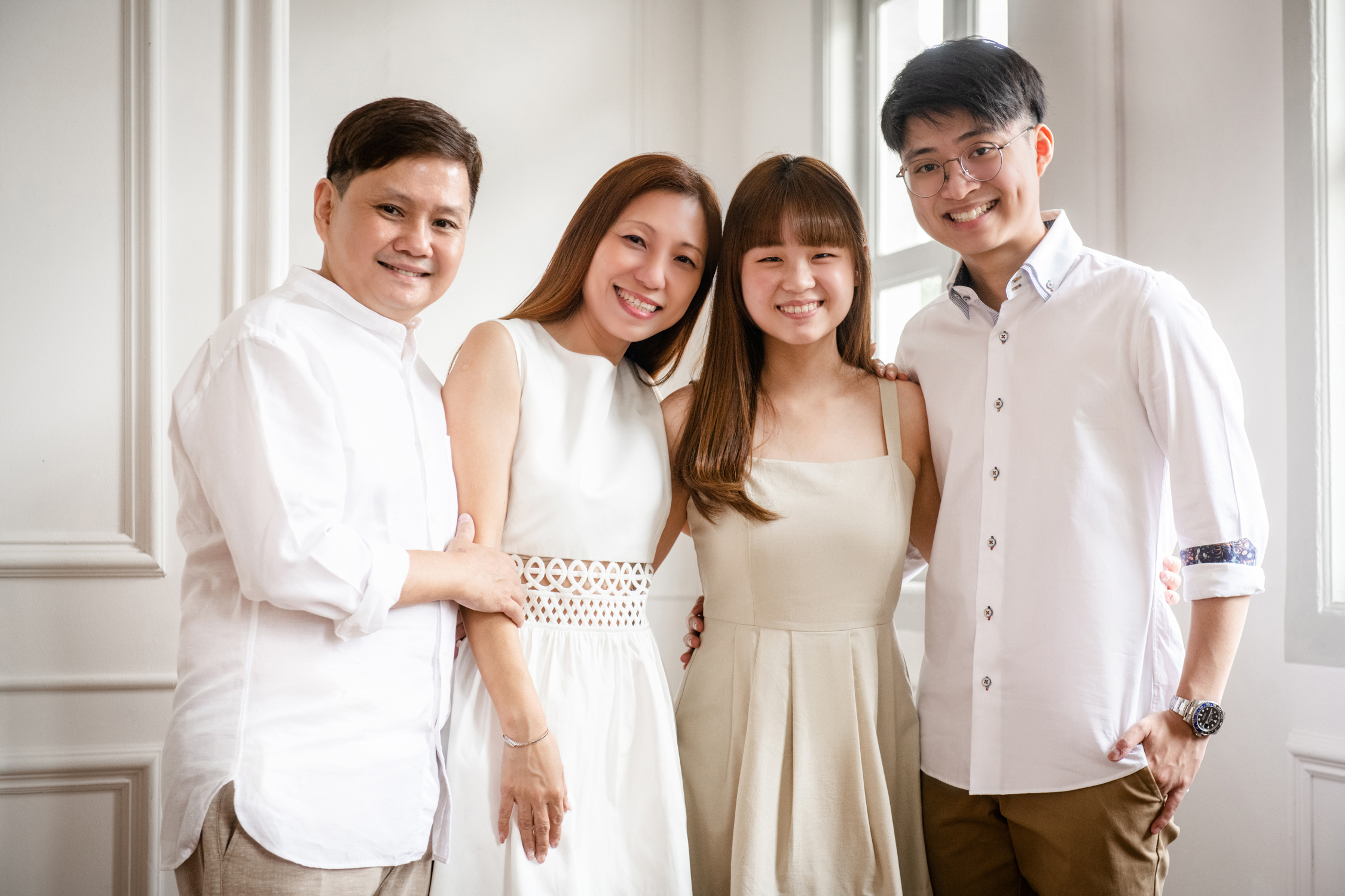 Graduation Photoshoot_07 Family of four dressed in white, standing in front of a white wall