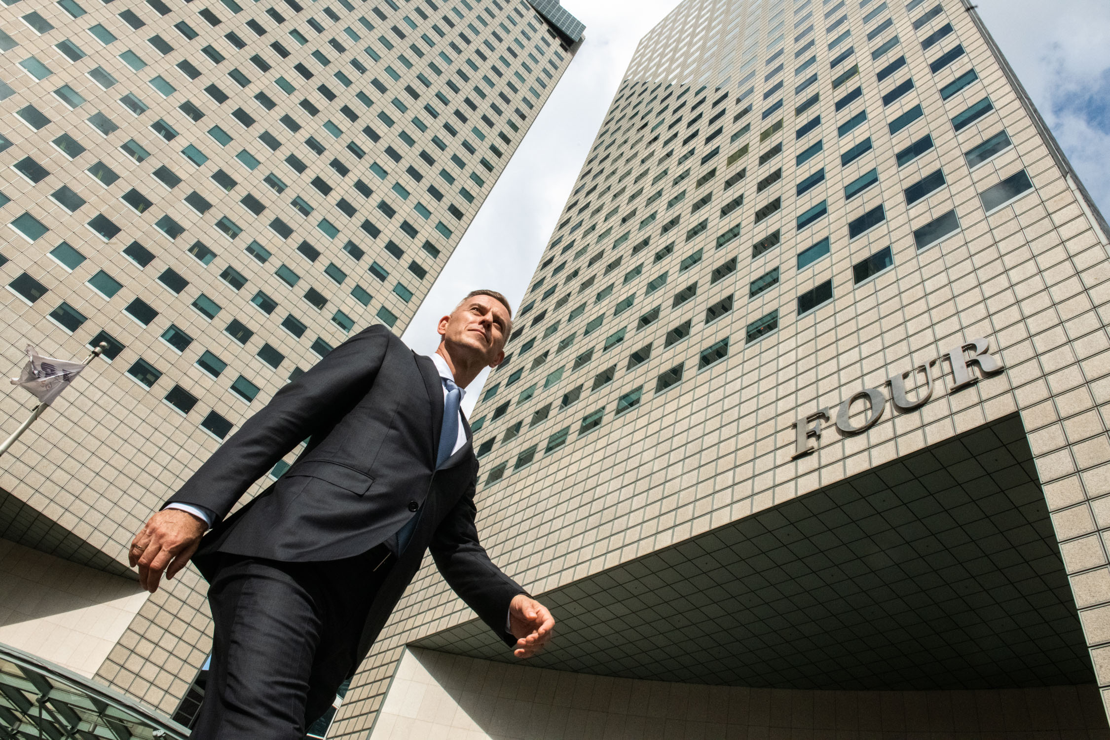Man in a formal business suit walking outdoors against a backdrop of office buildings in Singapore